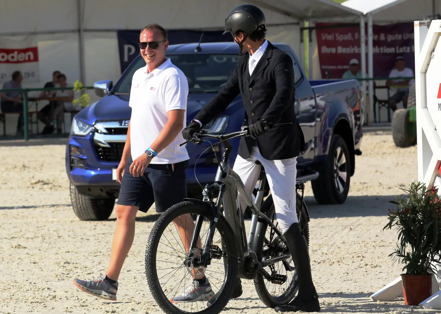 LRV Timmenrode e.V., Pferdeveranstaltungen, Kinderland, Ein Mann in Reituniform auf dem Fahrrad, im Gespräch mit einem anderen Mann